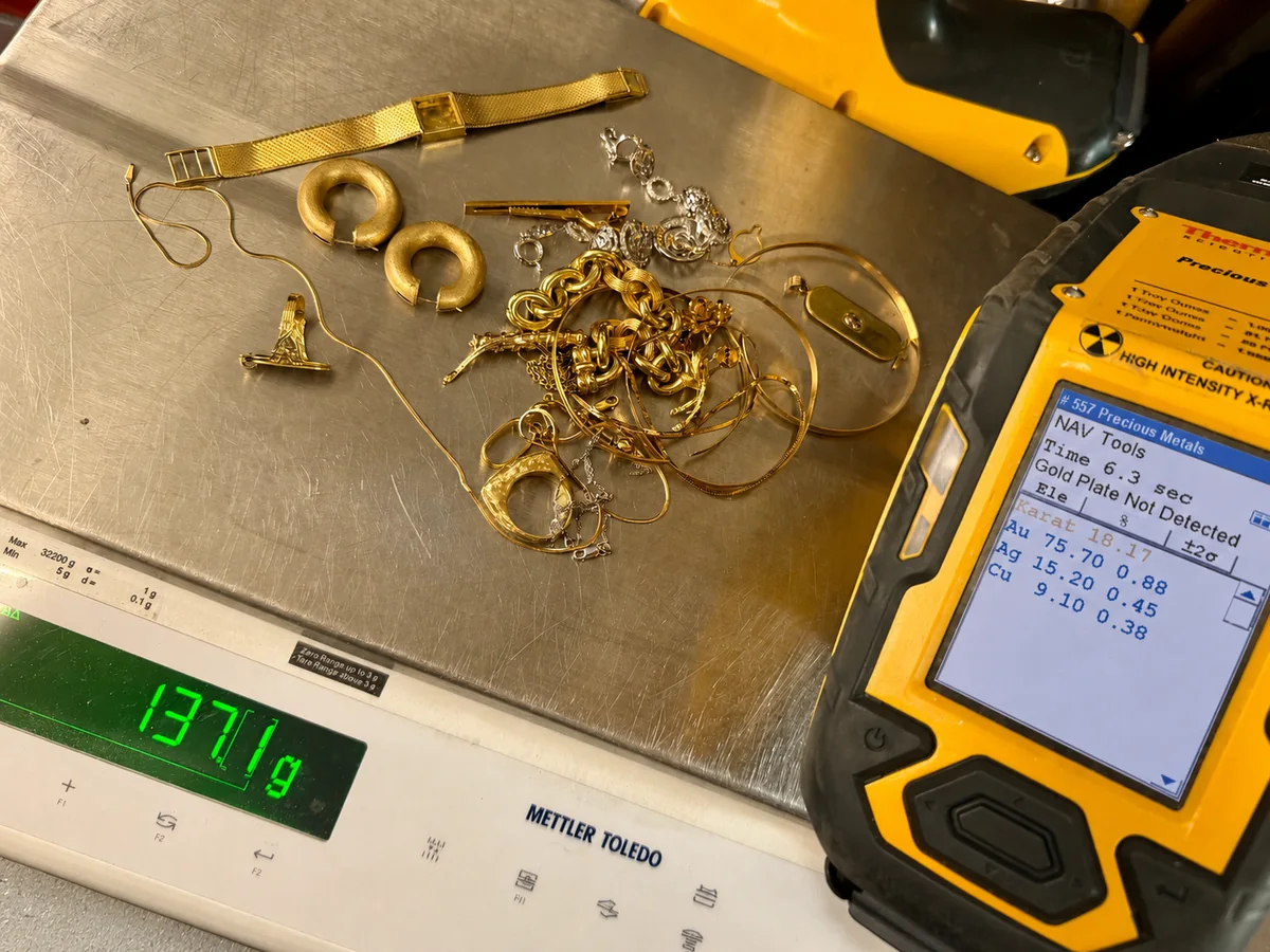 A lot of gold jewelry on our counter scale beside the XRF analyzer showing its purity readout