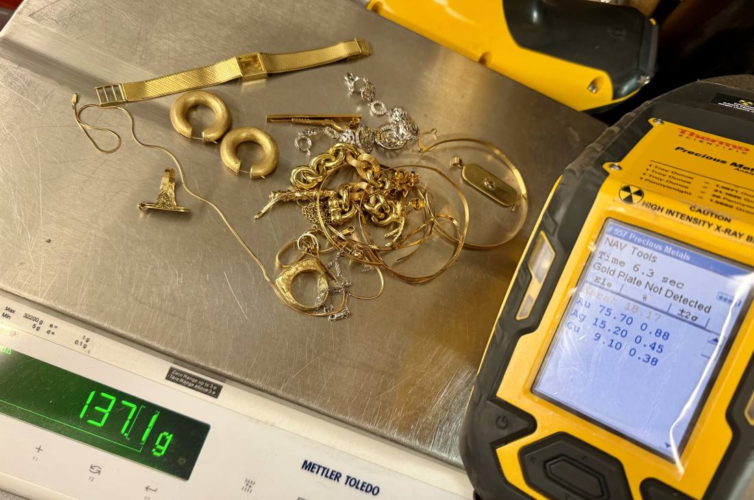 Niton XL2 XRF analyzer at our counter reading 18 karat gold (75.7% Au) beside a Mettler Toledo scale weighing a 137-gram lot of gold jewelry